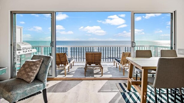 Un balcon avec vue sur l’océan, aménagé avec des chaises et une table.