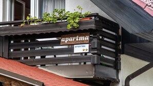Ein Holzbalkon mit einem Schild, auf dem 'apartma' steht, und drei Sternen.