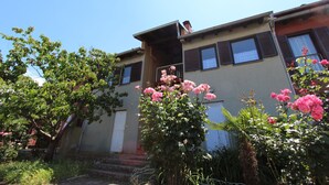 A two-story building with a balcony, surrounded by lush greenery and pink flowers. - Apartment Mitton 2 (Rovinj)