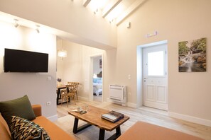 A modern living room with a flat-screen TV, a wooden coffee table, and a sofa with patterned cushions.