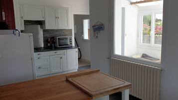 Een keuken met witte kasten, een magnetron, een broodrooster en een houten tafel.