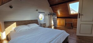 Een slaapkamer met een bed, raam, lamp en deur.