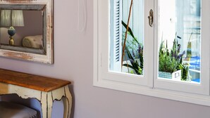 Une pièce avec une fenêtre à cadre blanc, une table en bois, un banc et un miroir accroché au mur.
