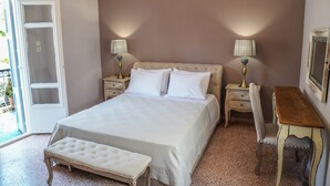 Une chambre à coucher avec un grand lit, des tables de chevet, un banc, un bureau et un lustre.