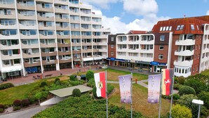 Ein mehrgeschossiges Gebäude mit Balkonen, einem begrünten Innenhof und Flaggen.