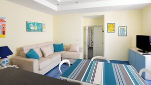 A modern room with a sofa, a striped table, a TV, and artwork on the walls. - Historic Charm with Modern Comfort near the Sea (Lacco Ameno)