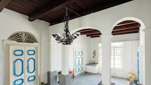 A spacious hallway with white walls, blue door handles, and a black chandelier. - Historic Charm with Modern Comfort near the Sea (Lacco Ameno)