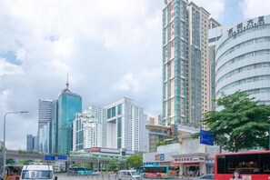 Une vue urbaine avec des immeubles modernes de grande hauteur, une tour imposante et un autobus rouge dans la rue.
