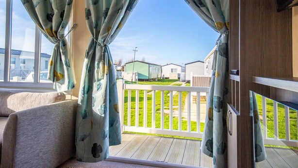 Ein gemütliches Zimmer mit Blick auf eine Terrasse und Mobilheime im Hintergrund.