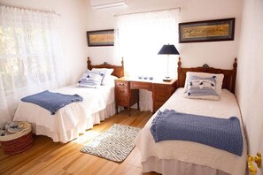 A bedroom with two beds, a desk, and a window with curtains. - Luxury Oceanfront 3BR Home with Sunset Views (Gregory Town)