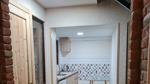 Een keuken met een backsplash van tegels in een visgraatmotief, een houten kast en een kleine koelkast.