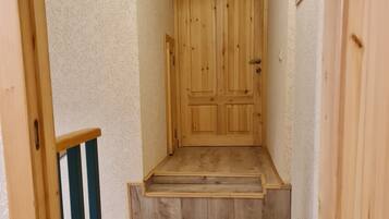 A wooden staircase leading to a door in a hallway with textured walls.