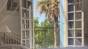 A room with a bed, a window with a view of a palm tree and a balcony. - Le Tassergal : Port Gimaud / St Tropez, 2 Chambres vue sur L'eau (Grimaud)