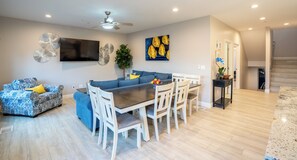 Un salon moderne comprenant un coin repas, un canapé et un téléviseur fixé au mur.