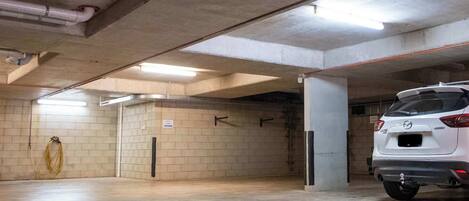 A parking garage with concrete walls and a white car parked in the foreground.