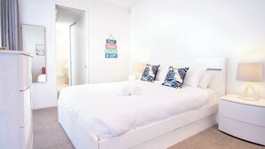 A hotel room with a large bed, white bedding, a bedside table with a lamp, and a wall sign with motivational phrases. - Live like a local In the heart of Moffat Beach (Moffat Beach)