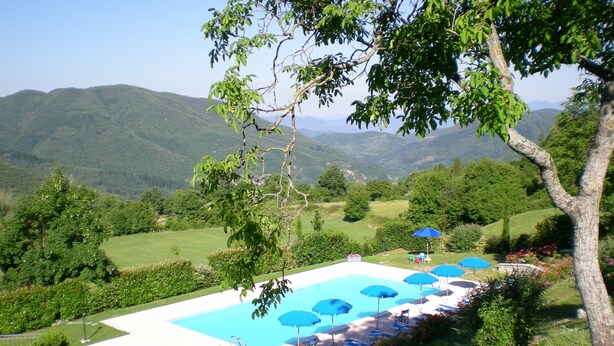 A pool area with multiple blue umbrellas and lounge chairs, surrounded by lush greenery and hills in the background. - Appartameto wi fi, Natura , Relax (minucciano)