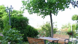 A park bench and a table in a garden with a tree and various plants. - Appartameto wi fi, Natura , Relax (minucciano)