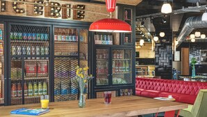 Interior de restaurante con barra de madera, sillas rojas y un banco con cojines rojos.