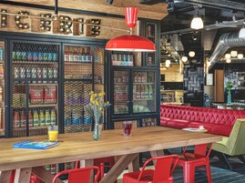 Interior de restaurante con barra de madera, sillas rojas y un banco con cojines rojos.