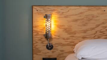 A wooden headboard with a wall-mounted light fixture and a power outlet below it.
