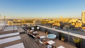 A rooftop terrace with lounge chairs, a hot tub, and a city view. - Brown Machne Yehuda (Jerusalem)
