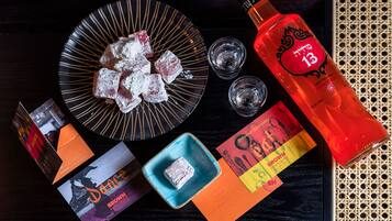 Una bandeja con cubitos de hielo, una botella de líquido rojo y varias cartas sobre una superficie de madera oscura.