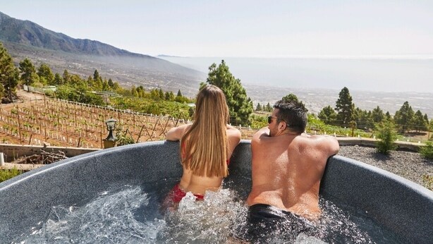 Ein Paar entspannt in einer Badewanne mit Panoramablick auf Weinberge und Berge.