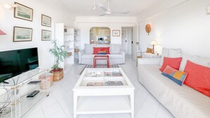 A modern living room with a white sofa, a glass coffee table, and a television. - Tranquility and Sea View at Meia Praia (Lagos)