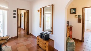 Ein Flur mit einem Holzkleiderschrank, einem Spiegel und einem gefliesten Boden.