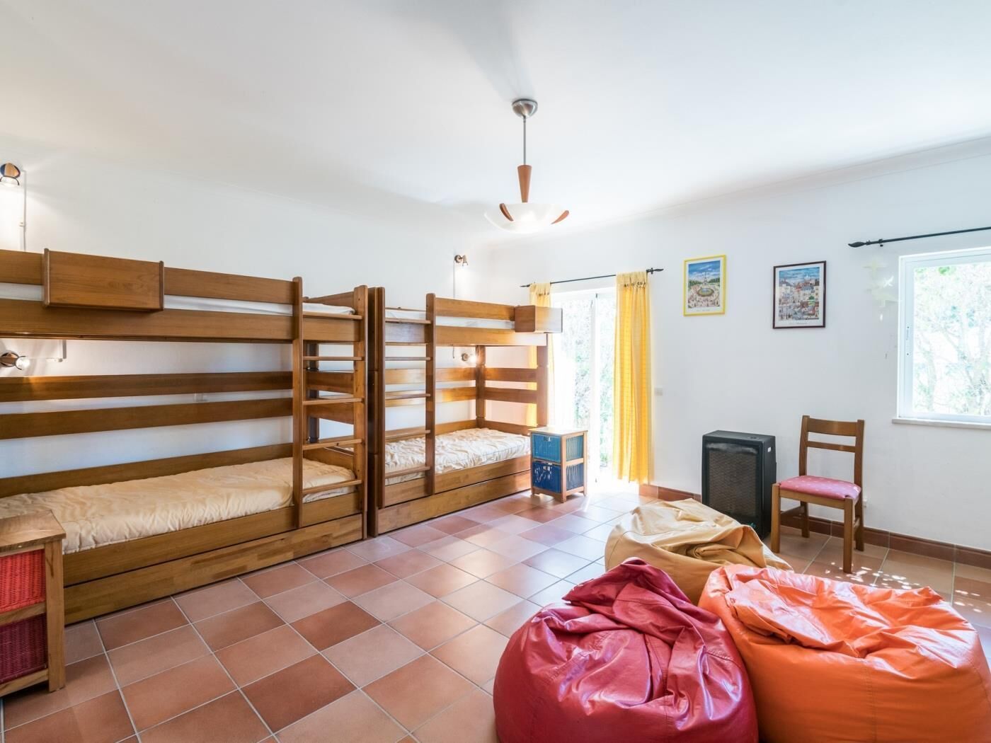 A dormitory room with bunk beds, a desk, a chair, and bean bags.