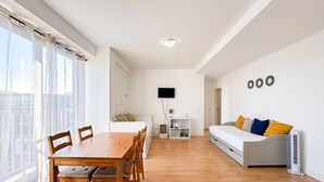 A modern apartment with a dining area, a sofa, a TV, and a view of the city. - Bright apartment next to main avenue and marina (Lagos)