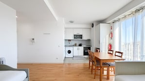 A modern apartment with a kitchen, dining area, and a large window with a view. - Bright apartment next to main avenue and marina (Lagos)