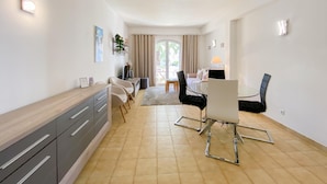Een moderne, goed verlichte kamer met een eethoek, een bank en een bureau.