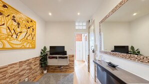 Ein modernes Hotelzimmer mit großem Spiegel, Flachbildfernseher, einer Wand mit Holzvertäfelung und einem großen Kunstwerk.