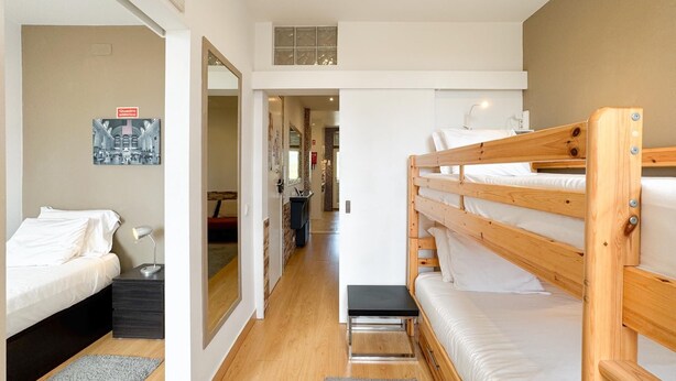 Ein modernes Hotelzimmer mit Etagenbett, Schreibtisch und Spiegel.