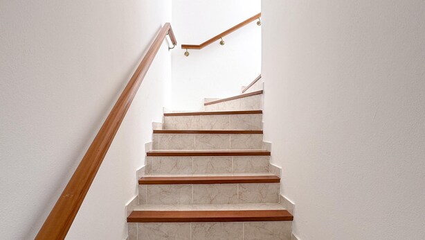 A staircase with wooden handrails and white marble steps.