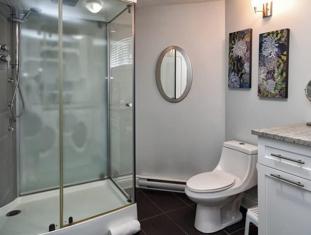 Et moderne badeværelse med bruseniche, toilet og vask med bordplade.