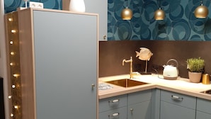 A modern kitchen with a blue cabinet, a sink, and pendant lights. - Blaue Welle - Gemütlichkeit mit Stil (Varel)