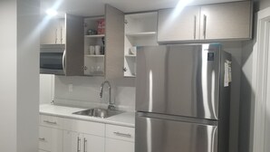Una cocina moderna con electrodomésticos de acero inoxidable, armarios blancos y un lavamanos empotrado.