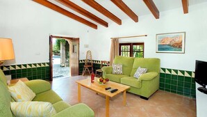 A living room with green sofas, a wooden coffee table, and a painting on the wall. - Villa Almendra Boi, Mallorcan country house with modern touches (Pollença)