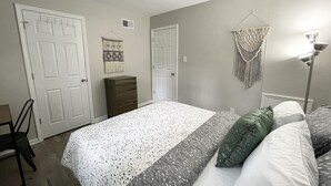Een slaapkamer met een bed, een dressoir en een kledingkast.