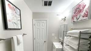 Een kleine, schone badkamer met toilet, wastafel, handdoekrek en een deur.