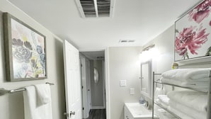Un baño con tocador blanco, perchero y espejo.