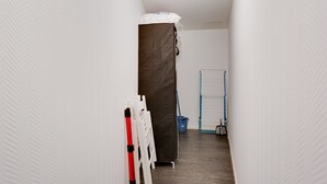 A narrow hallway with a mattress, a white chair, a blue bucket, and a blue mop leaning against the wall. - La Bridole - Apt rénové proche Gare (Vitré)