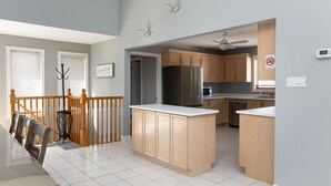 Una cocina moderna con armarios de madera, un refrigerador de acero inoxidable y una encimera blanca.