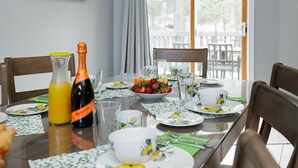 Una mesa de comedor preparada con platos, vasos, una botella de zumo de naranja y una botella de champán.
