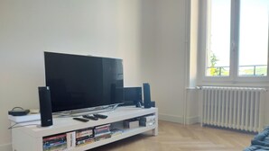 Una sala de estar con televisor de pantalla plana, parlantes y un mueble blanco para entretenimiento con libros.