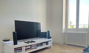 A living room with a flat-screen TV, speakers, and a white entertainment unit with books.