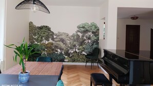 Una sala de estar moderna con un piano, una mesa de comedor con sillas y un mural grande en la pared.